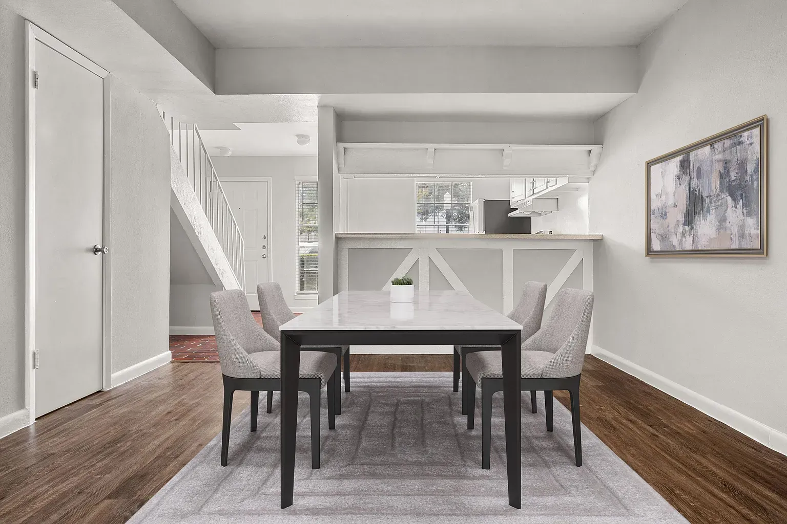 Interior dining area in an apartment with a marble table and six gray chairs.