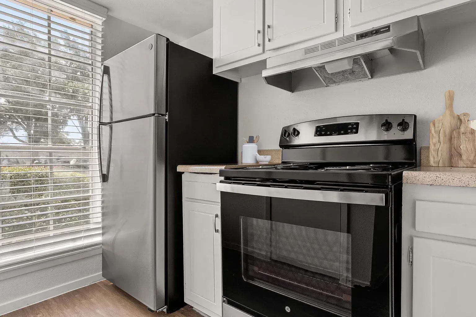 Kitchen with stainless steel refrigerator, range, and white cabinets.