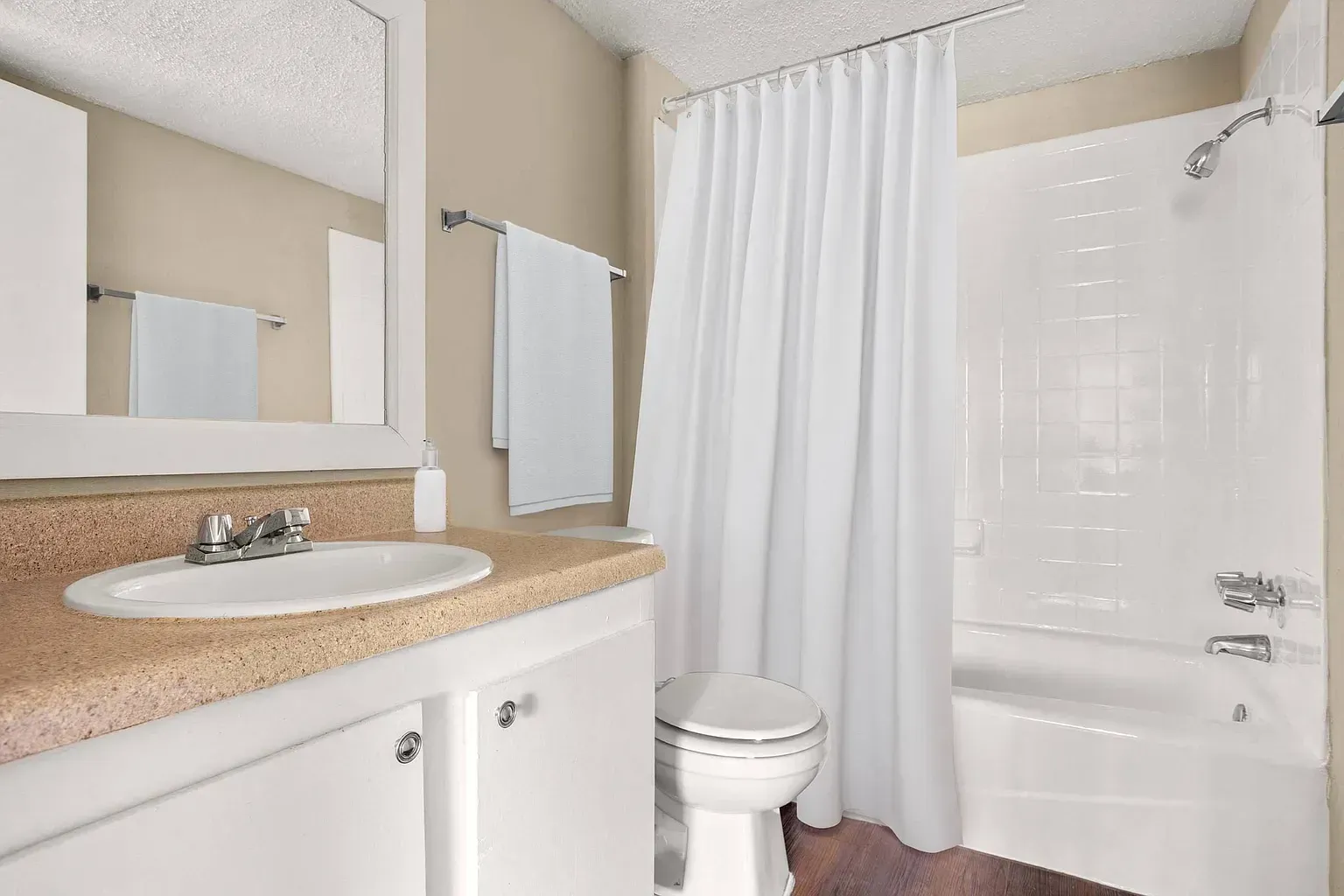 Bathroom with sink vanity, mirror, toilet, and bathtub with shower curtain.