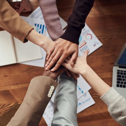 A group of people putting their hands together in a circle