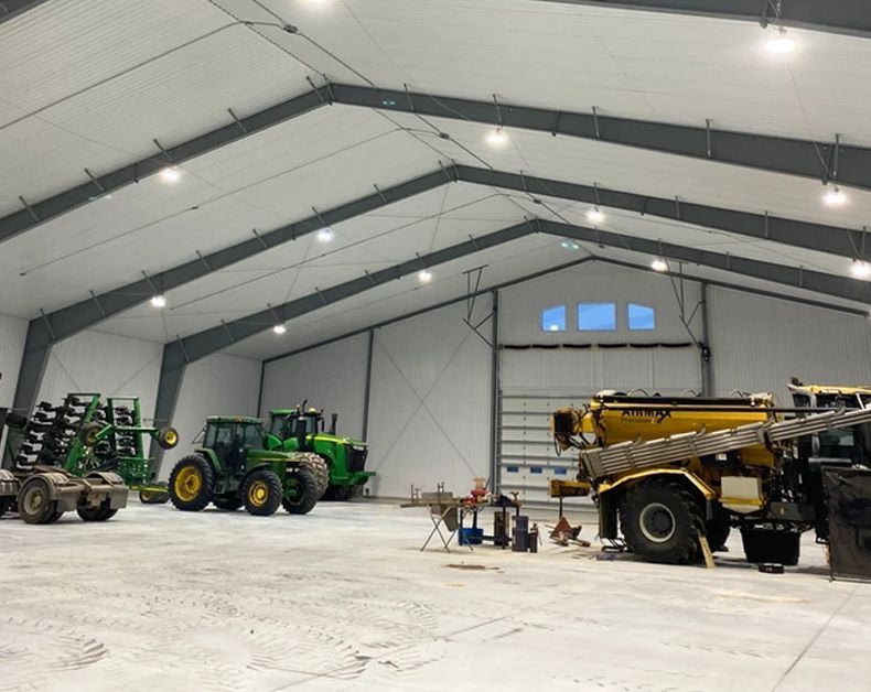 A large warehouse with tractors parked inside of it.