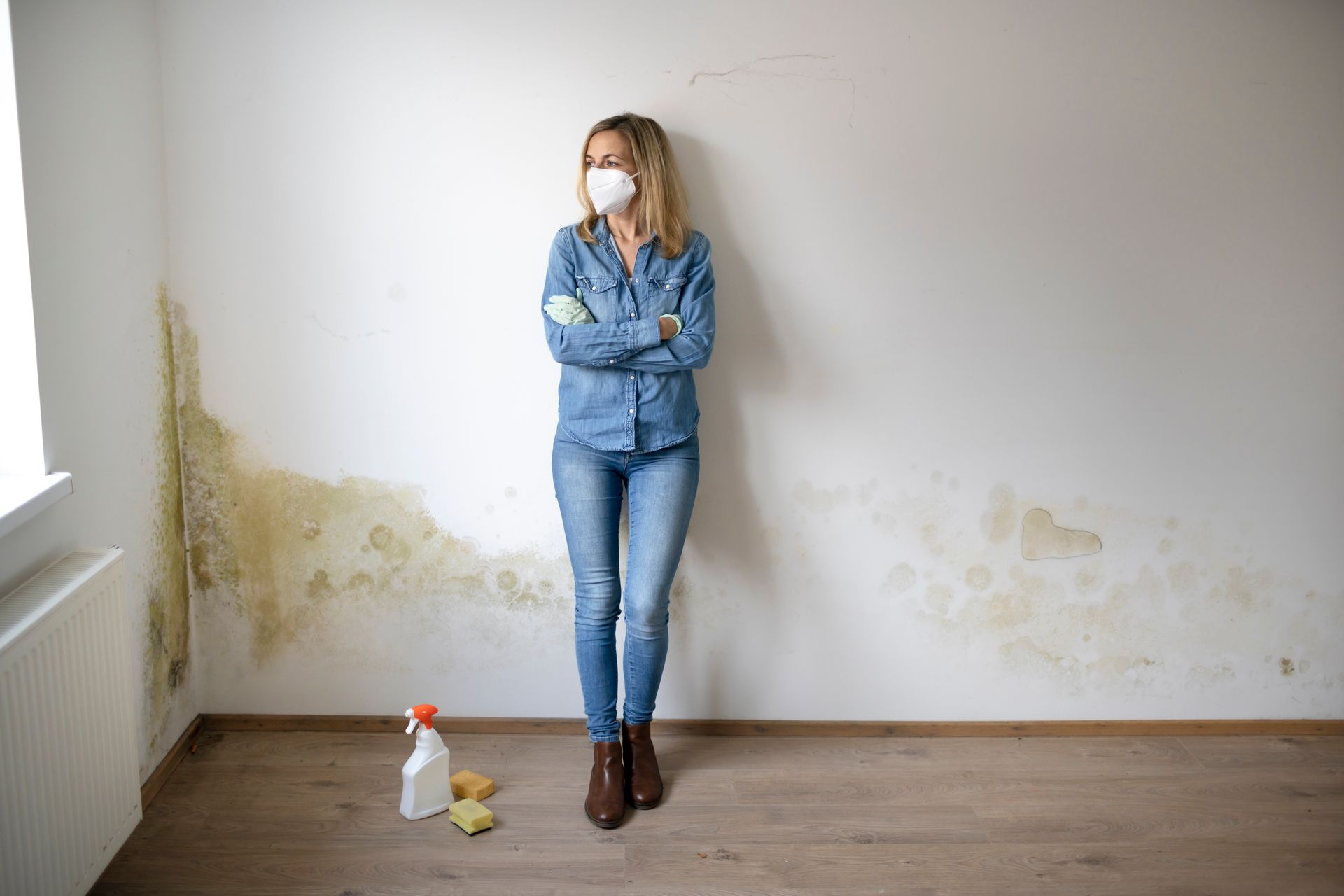 Person standing beside internal wall showing damp staining and mould growth