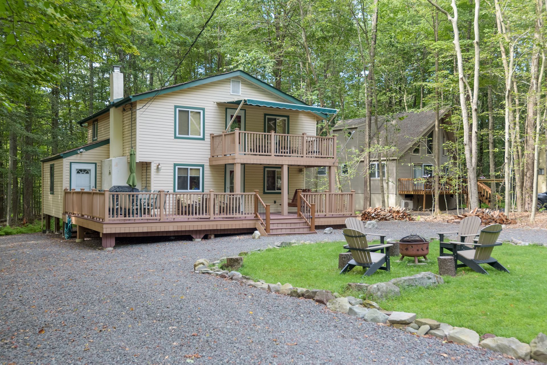A house with a large deck and a fire pit in front of it.