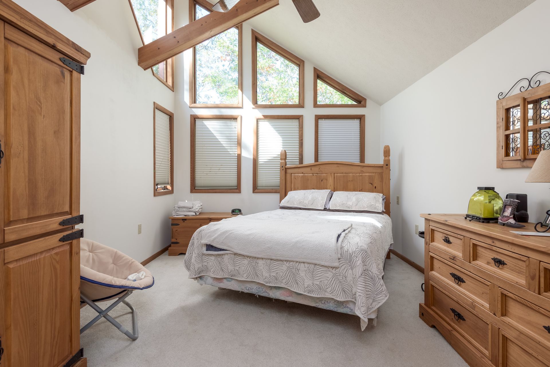 A bedroom with a king size bed , dresser , mirror and chair.