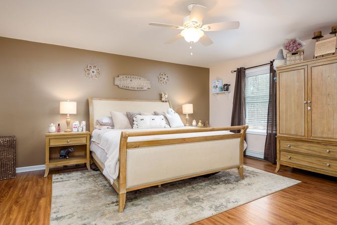 A bedroom with a bed , nightstands , cabinets and a ceiling fan.
