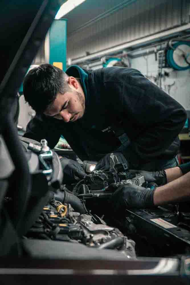 a mechanic looking under the hood of a car doing mobile auto repair