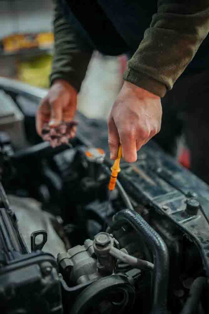 a mechanic checking the oil dipstick in a car
