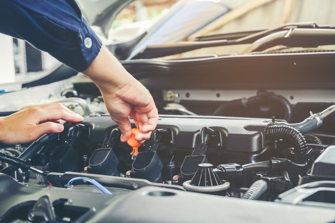 mechanic pulling the oil dipstick out of an engine bay