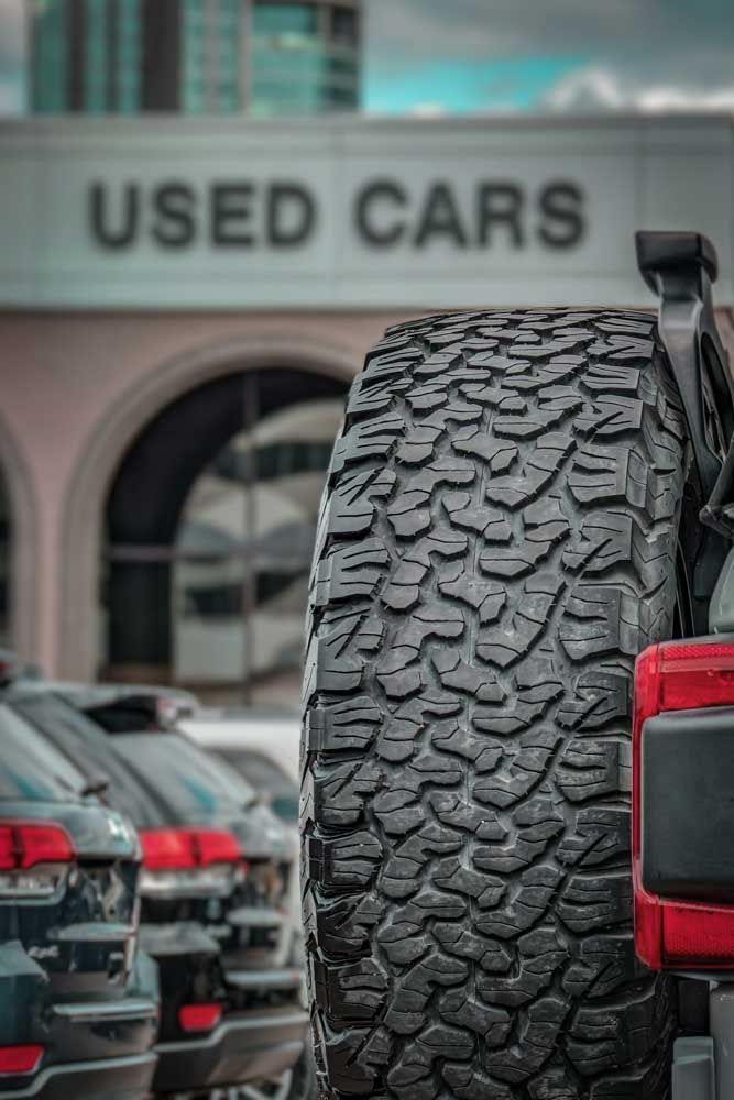 Close up of the rear of a car and a tire at a used automotive lot.
