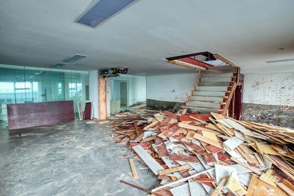 An empty room with a pile of wood and a staircase.