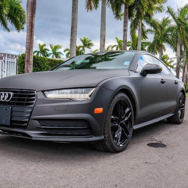 A black audi is parked on the side of the road