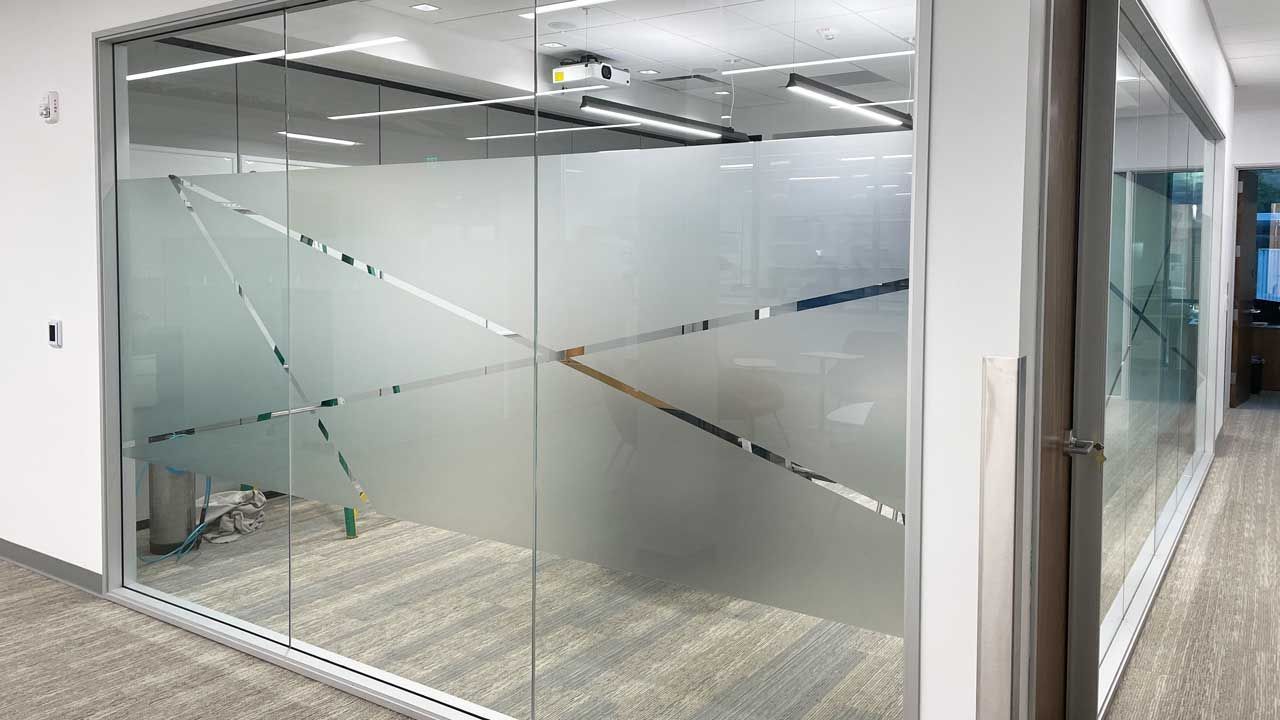 A hallway with a glass wall and a projector on the ceiling.