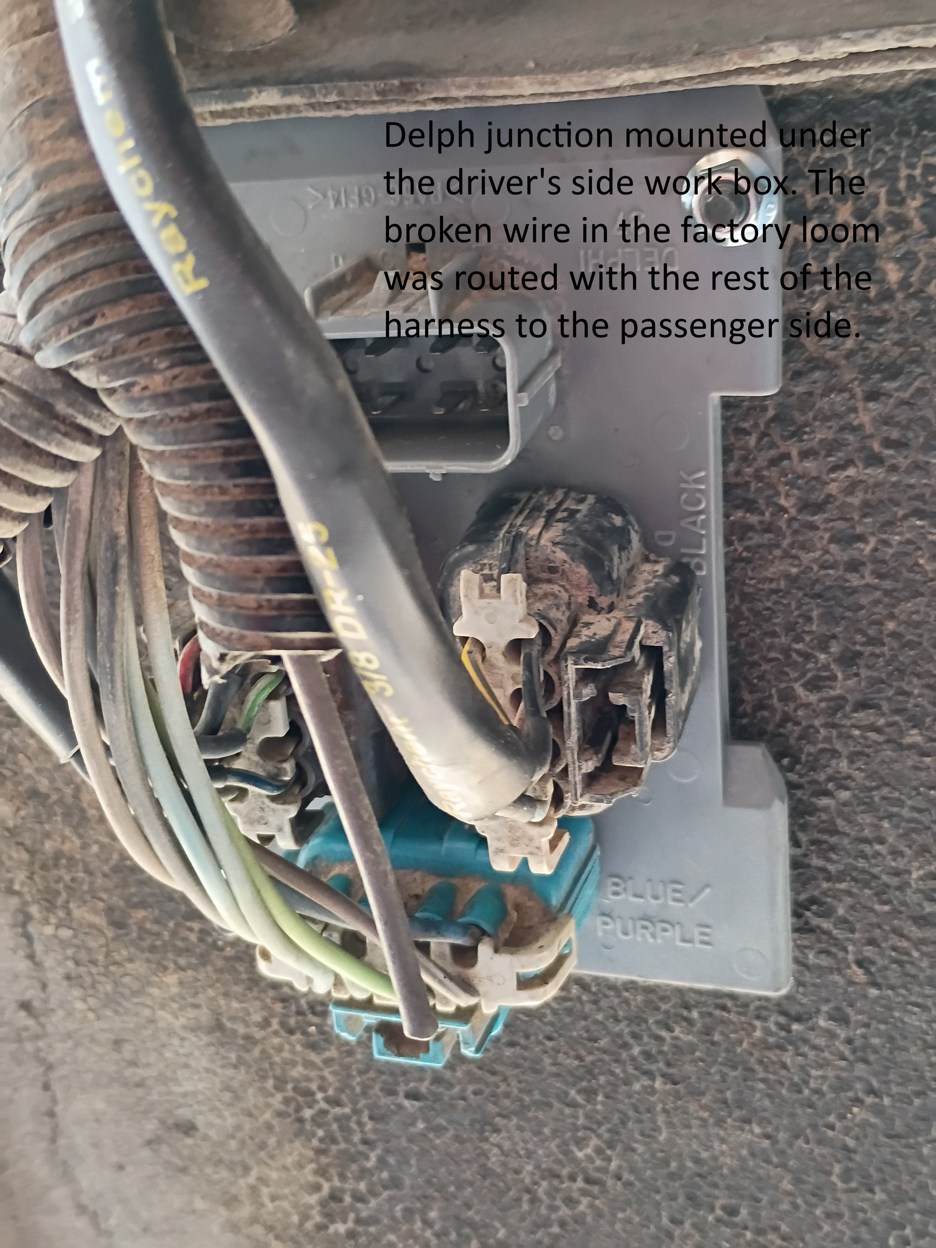 Damaged electrical junction box with exposed wires and torn insulation on a wall.