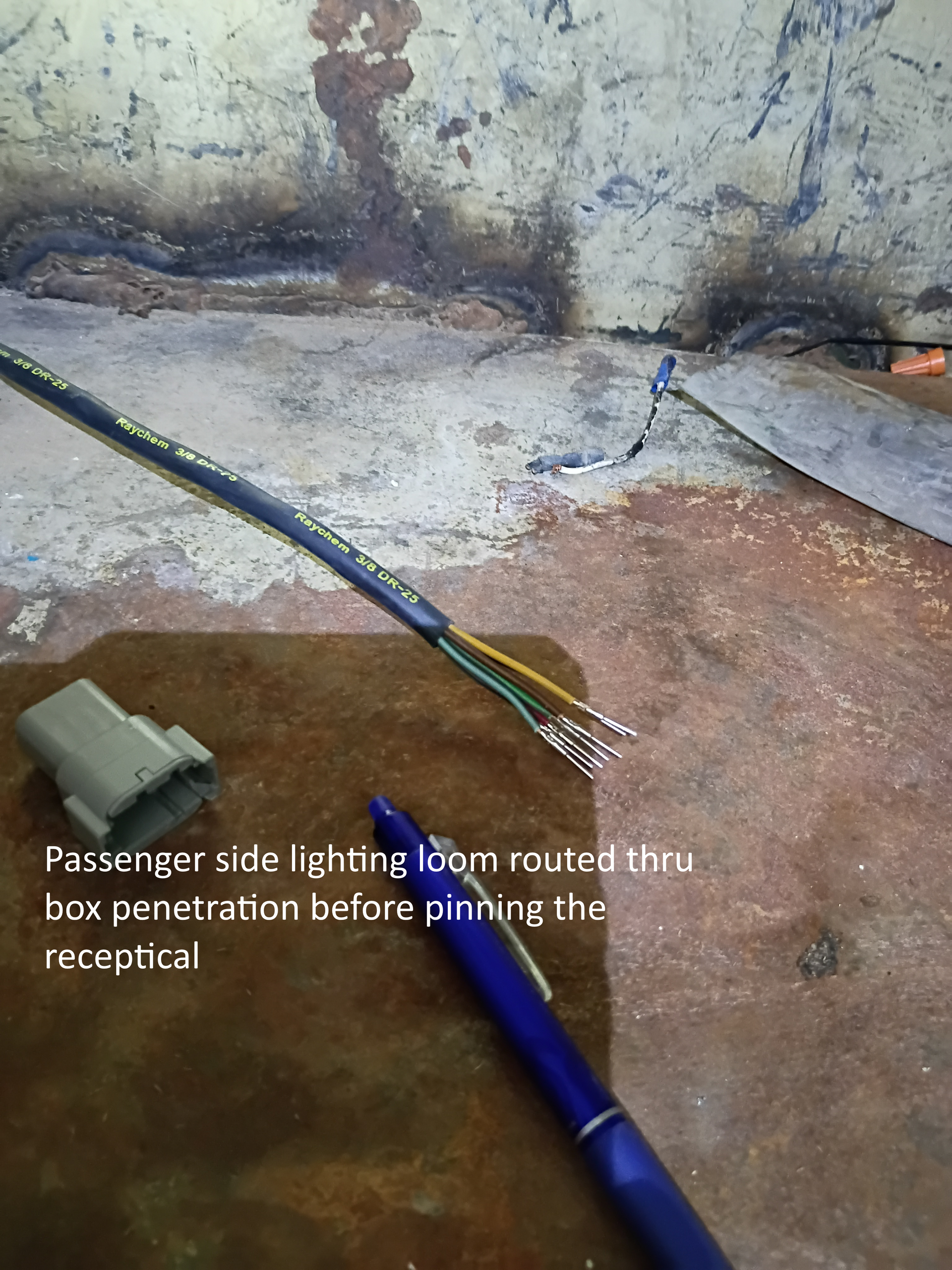 Fishing rod beside a rough concrete wall, with a small connector and text overlay on the floor.