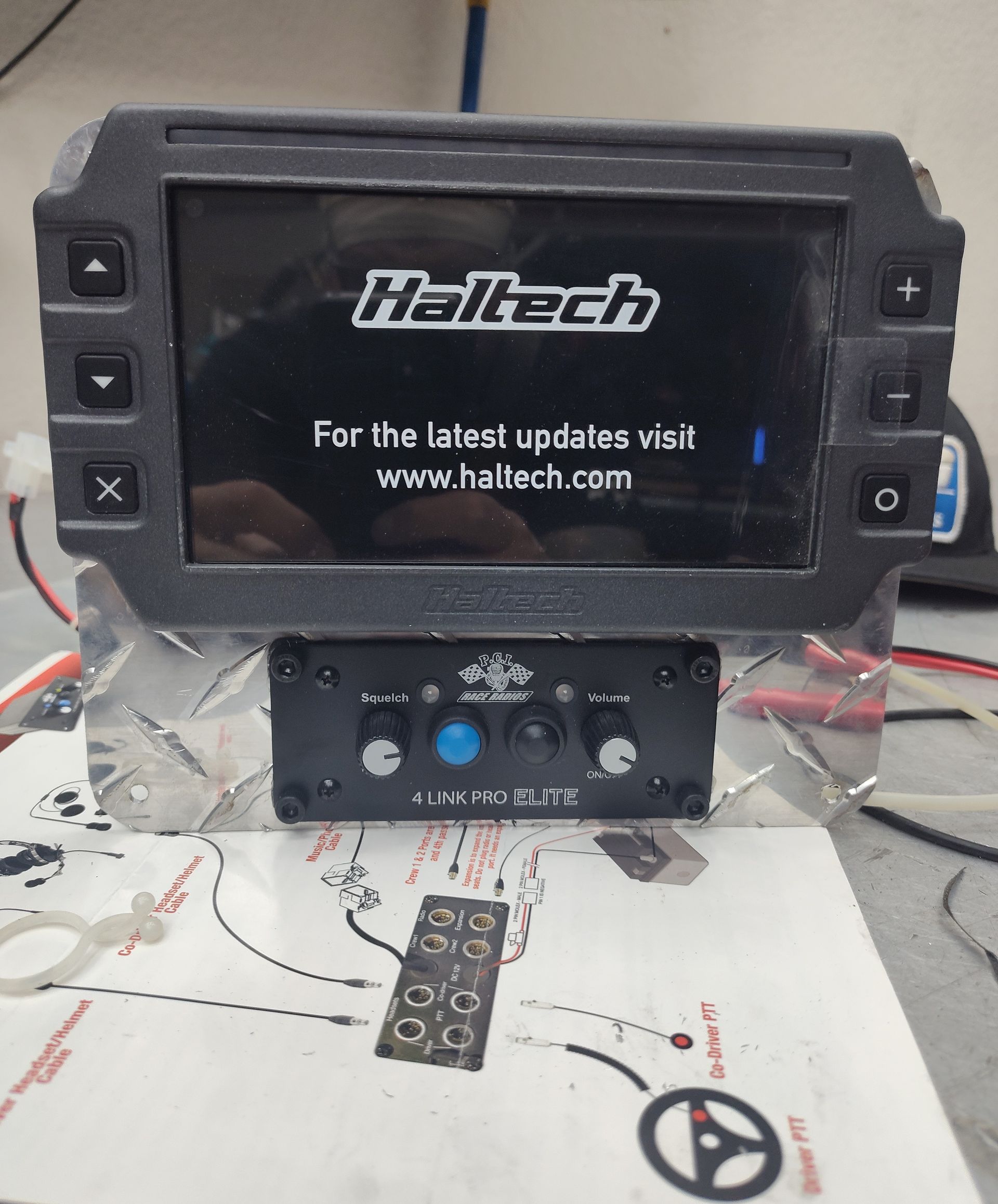 Haltech touchscreen tuner unit with black buttons and wiring on a workbench