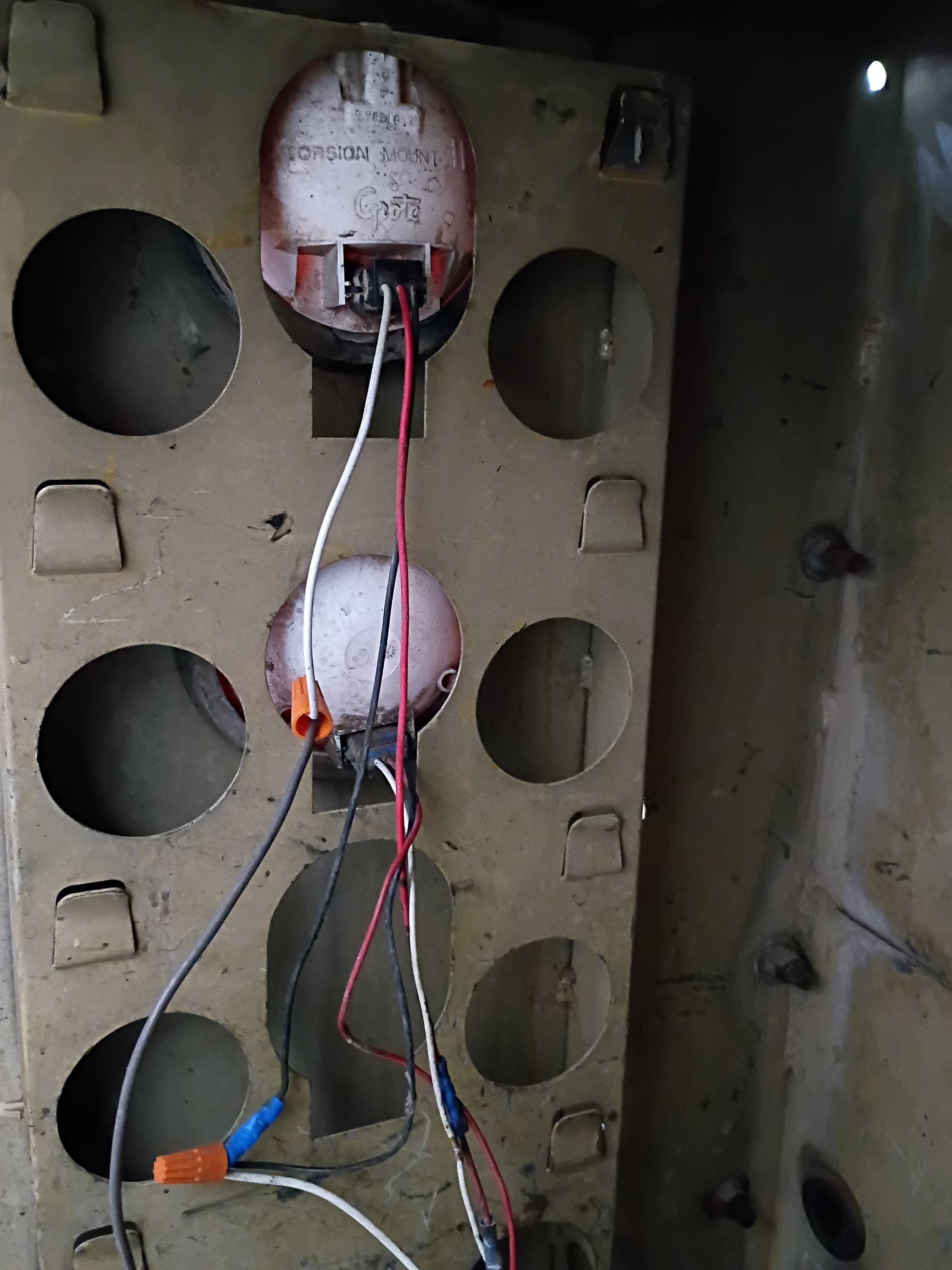 Interior of an electrical panel with exposed wires, sockets, and a central round device mounted on a metal backplate
