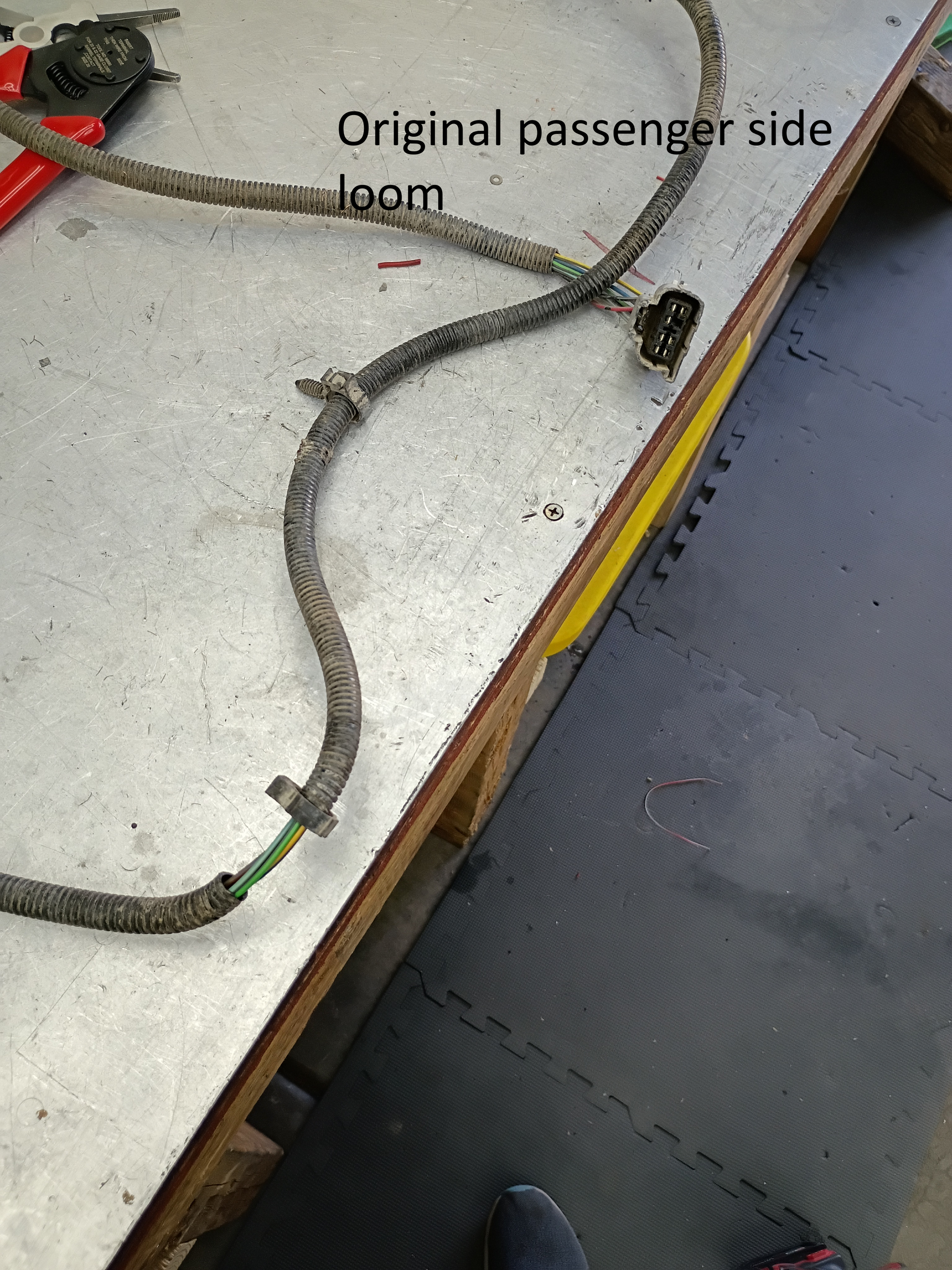 Damaged passenger-side door wiring harness on a workbench, with clipped connectors and labels visible