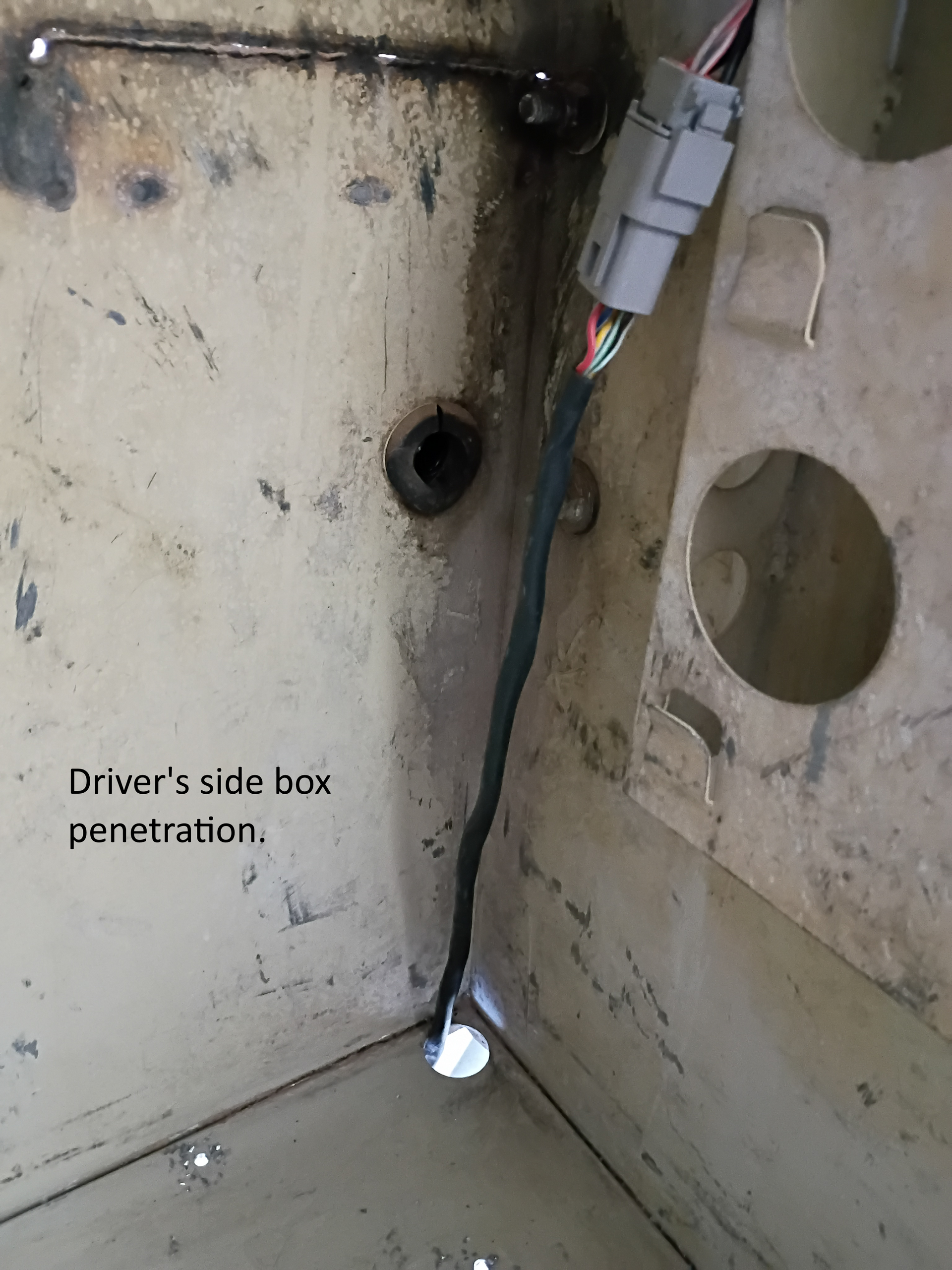 Close-up of a dirty wall corner with a driver’s side box penetration and exposed cable.