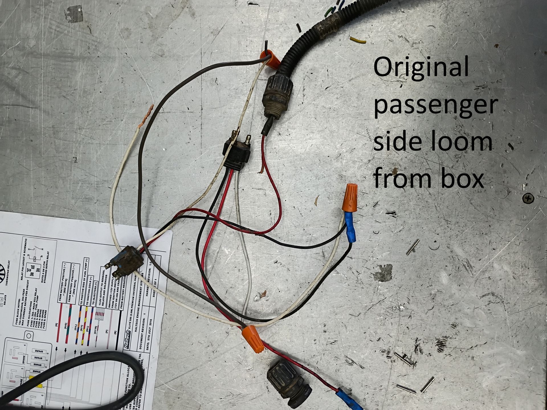 Wiring harness with red and black cables on a concrete floor, labeled “Original passenger side loom from box.”