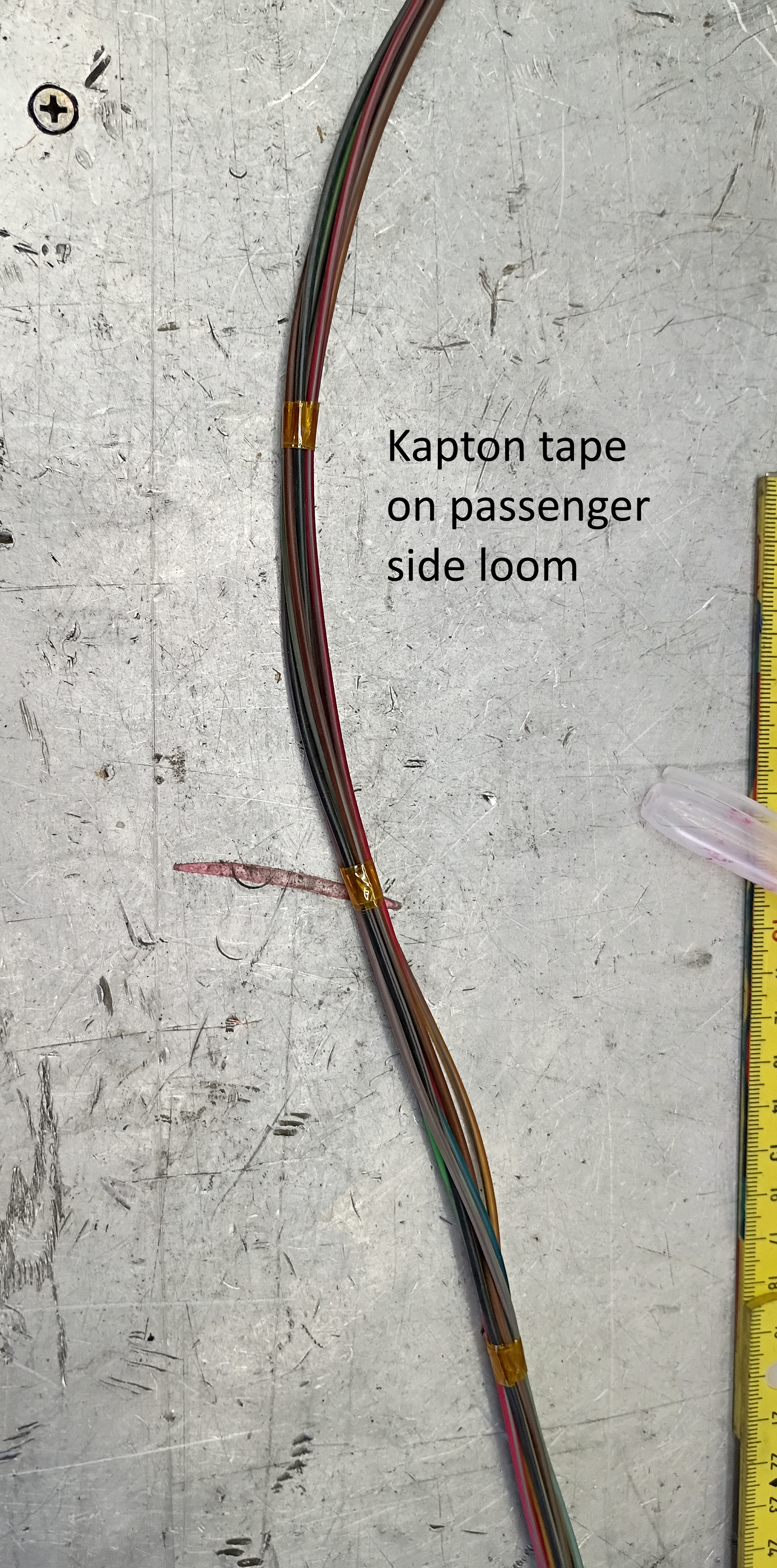 Colored cable on concrete floor labeled “Kaptan tape on passenger side loom”