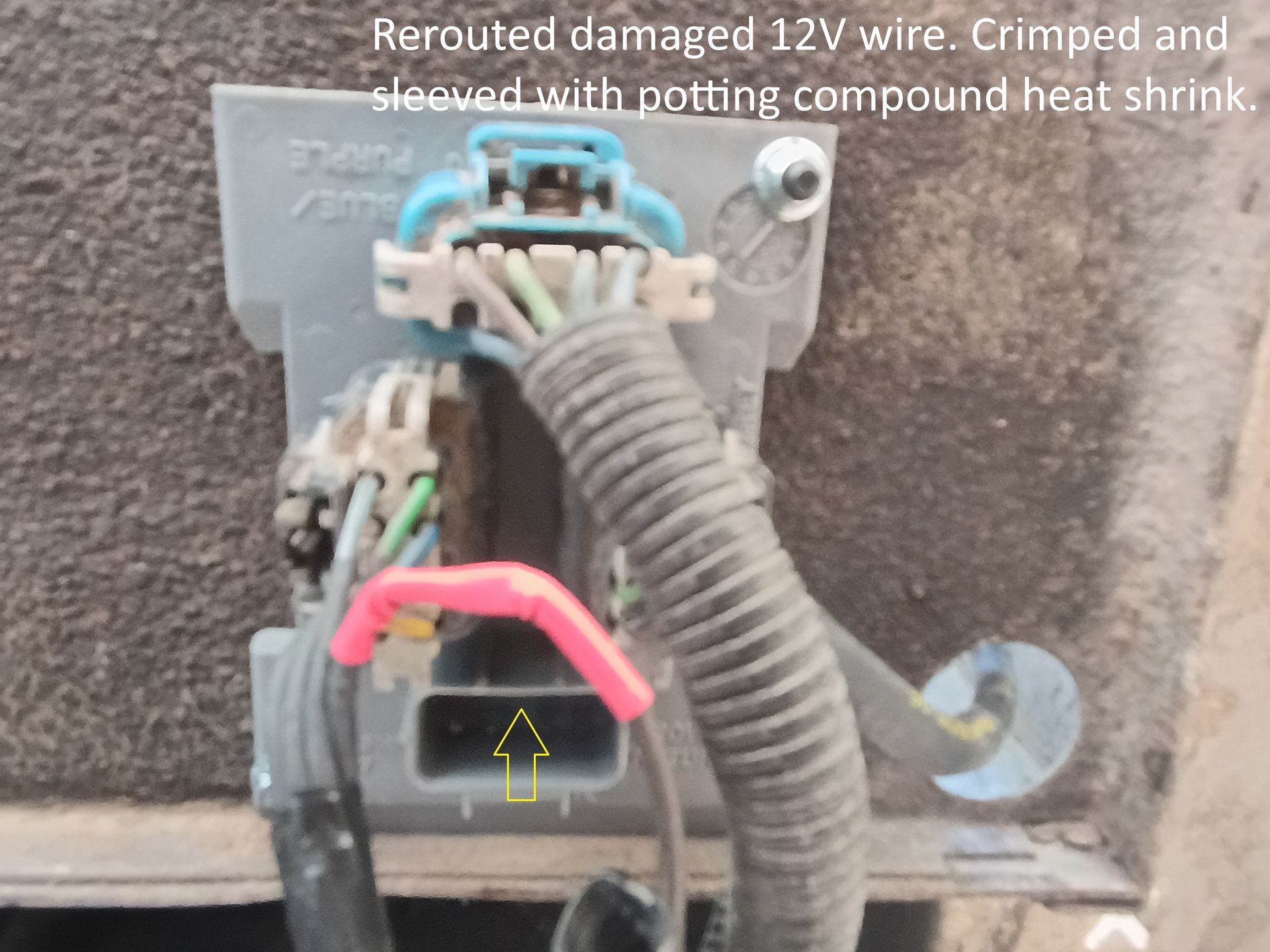 Close-up of repaired wiring harness with heat-shrink tubing and pink tape on a metal panel.
