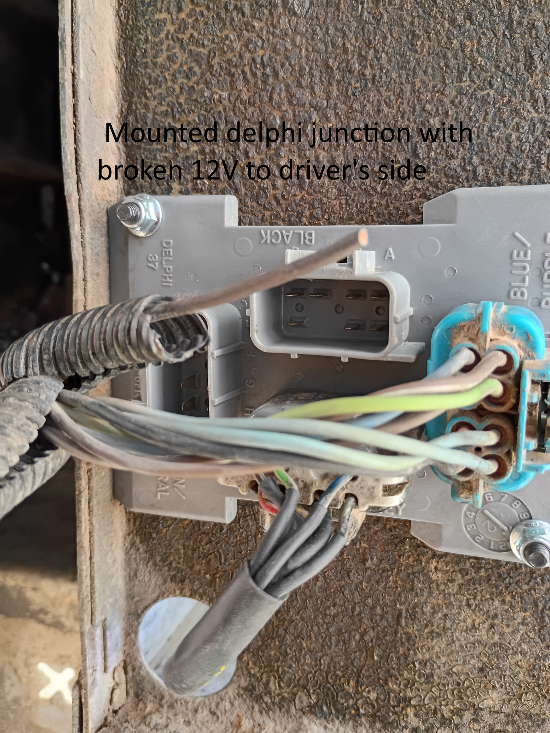 Mounted junction box with exposed wiring and broken connector, viewed close up on a wall.