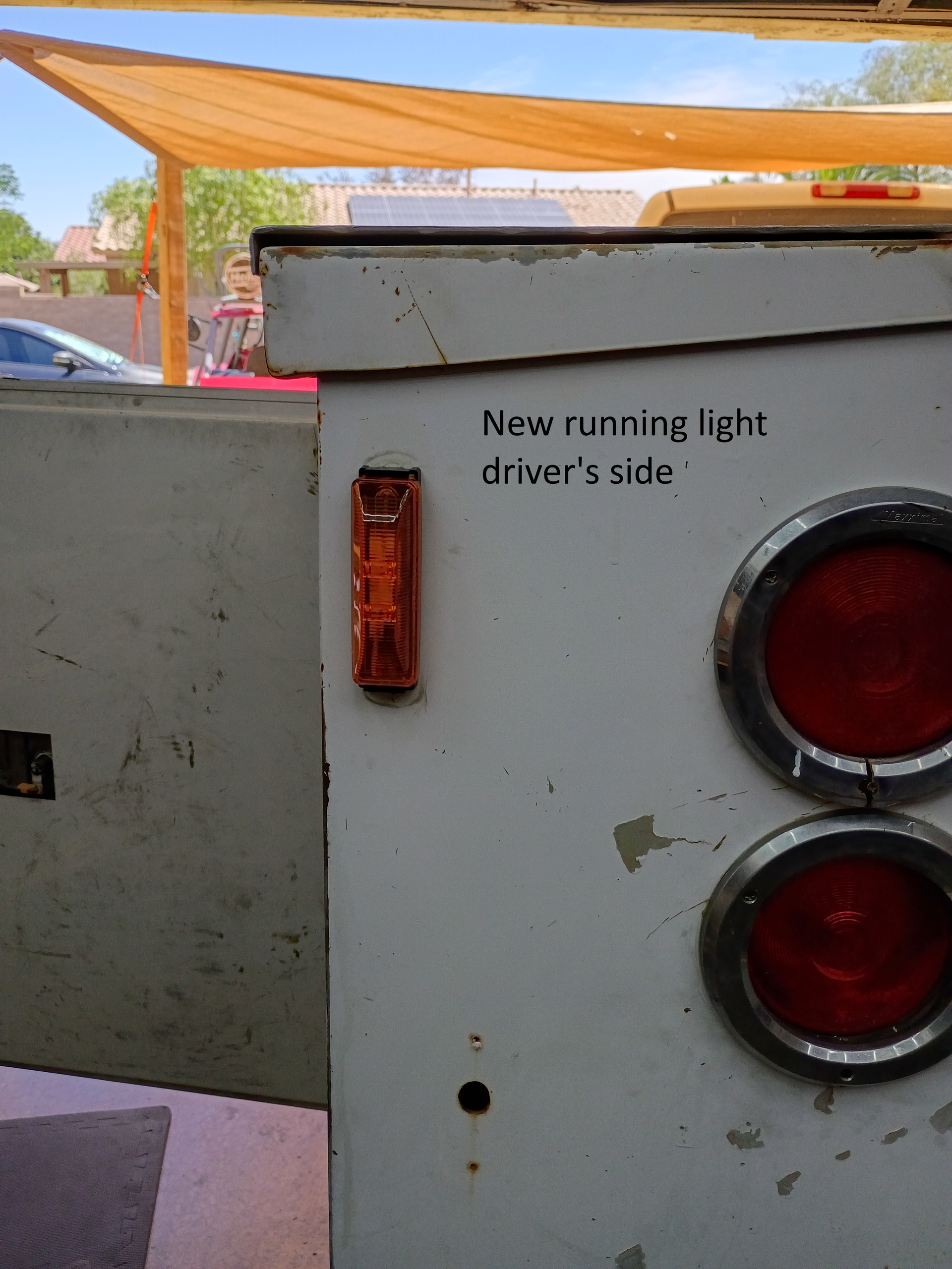 Close-up of a truck rear with a note reading “New running light driver’s side” and two red taillights.