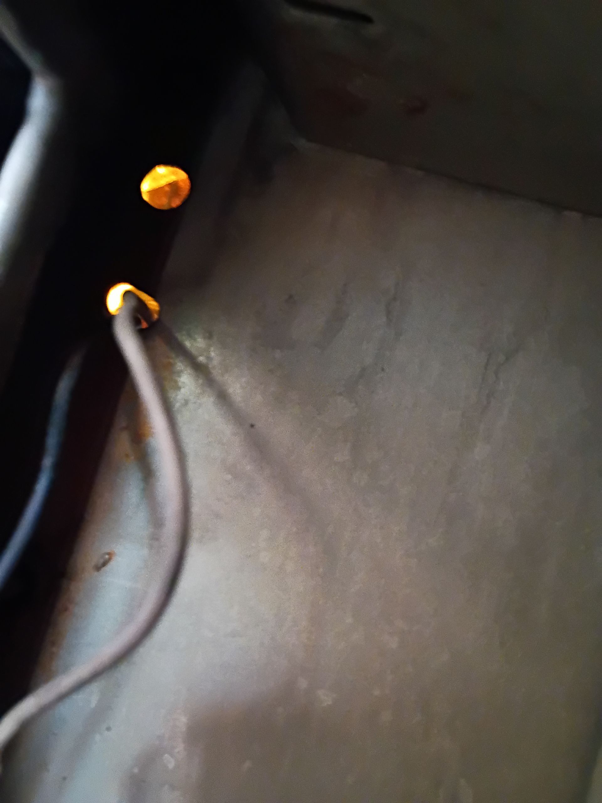 Close-up of black fabric with a gray cord and two orange cable ends near the top left.