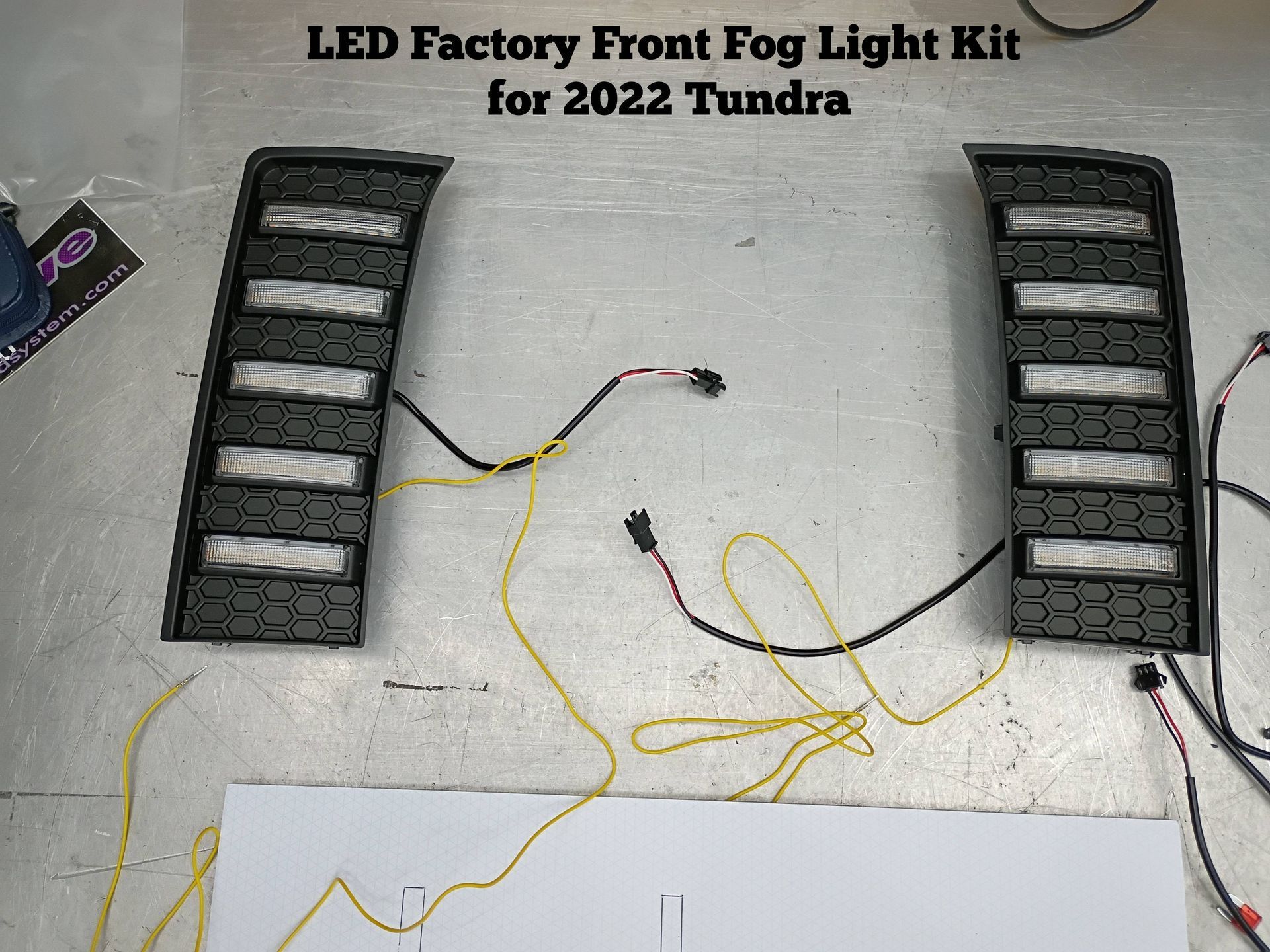 LED factory front fog light kit for 2022 Tundra with two black light bars and yellow wiring on a floor
