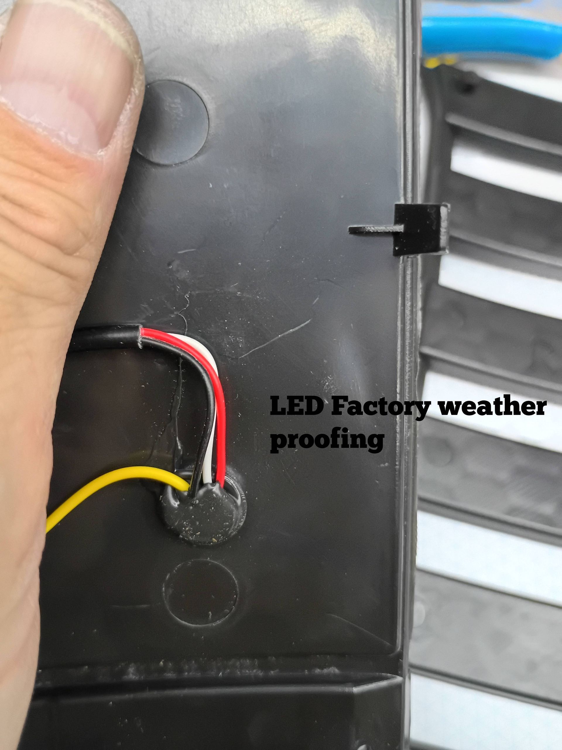 Close-up of black LED light housing with red and yellow wires and “LED Factory weather proofing” label