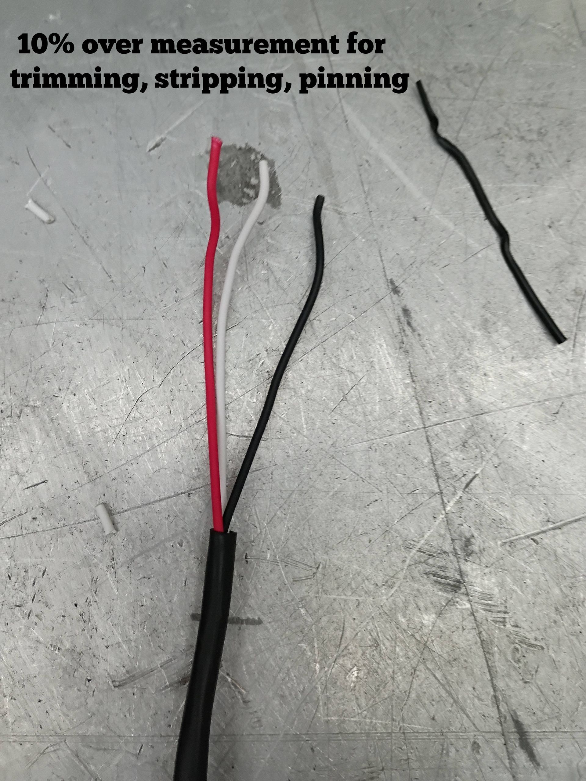 Red and black wires with exposed end on a workbench; text notes 10% over measurement for trimming, stripping, pinning.