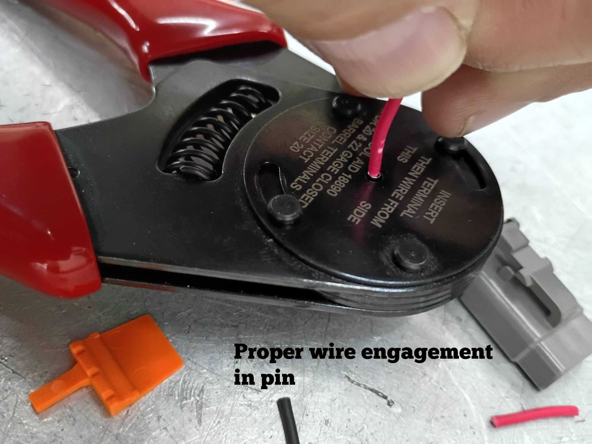 Close-up of red-handled pliers stripping a wire into a connector, with “Proper wire engagement in pin” text.