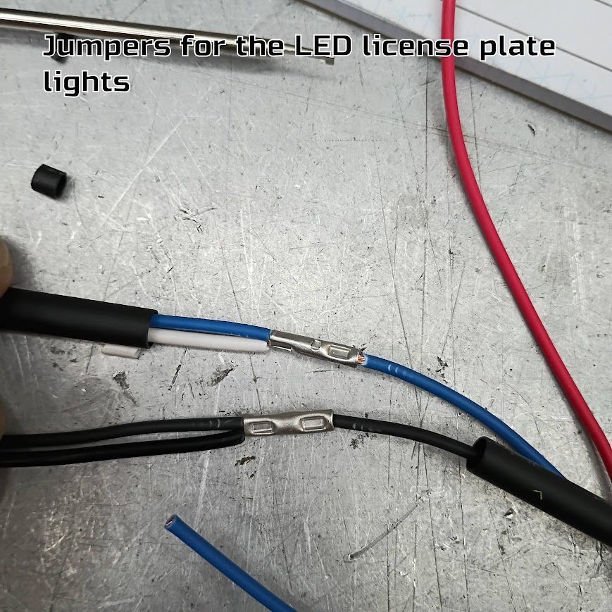 Blue and black wires with crimp connectors on a gray surface, labeled for LED license plate lights