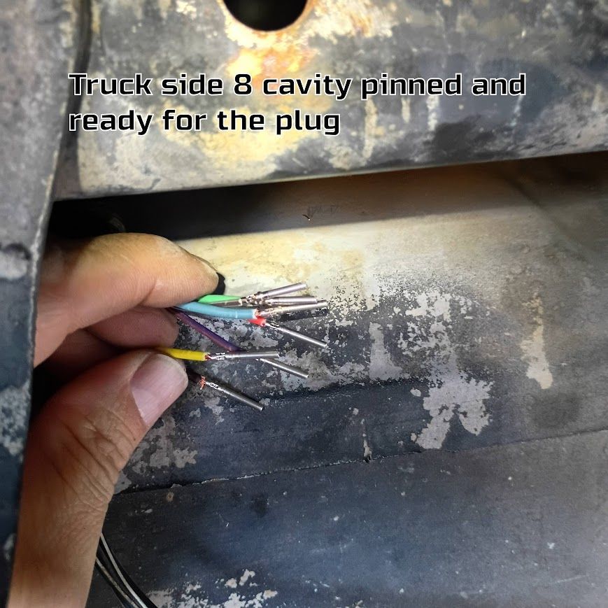 Hand holding multicolored wires inside a truck side 8-cavity connector opening
