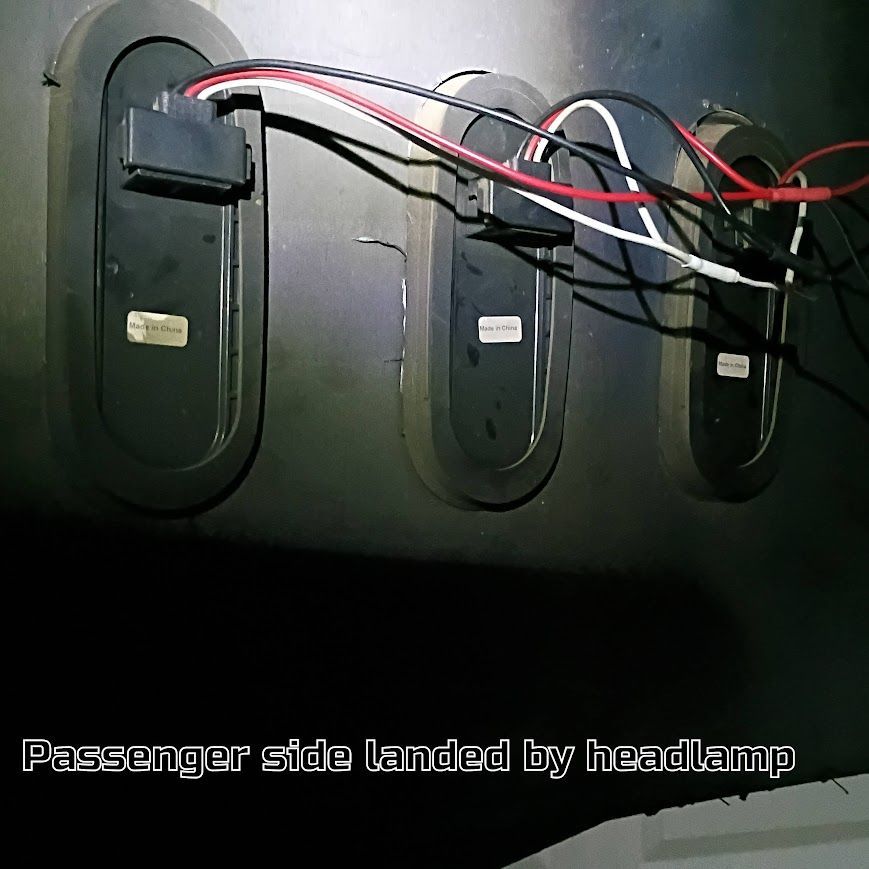Cables and connectors routed through three oval access panels on a black passenger-side car interior panel.