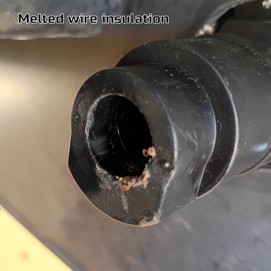 Melted wire insulation on a black cable end, with burn damage visible inside the opening.