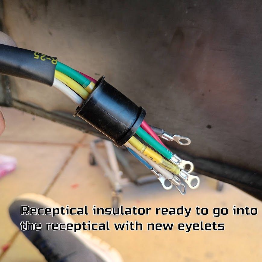 Black cable with colored wires and ring terminals wrapped in a black sleeve on a tiled floor.