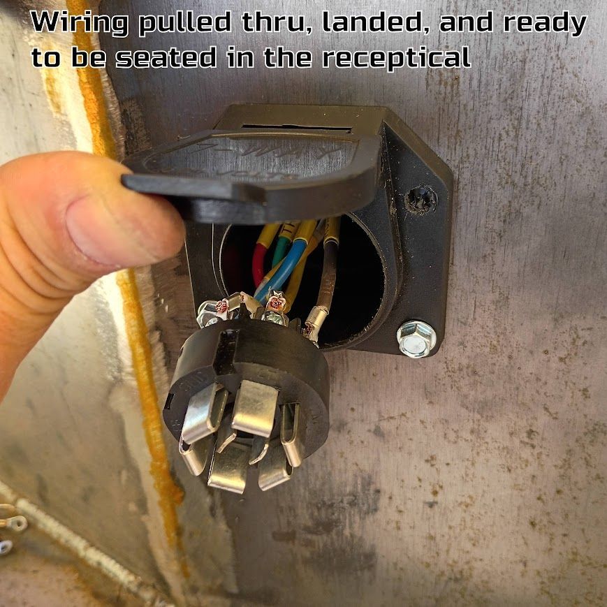 Electric wiring pulled through a wall receptacle box, ready for seating, with a hand holding the cover open.