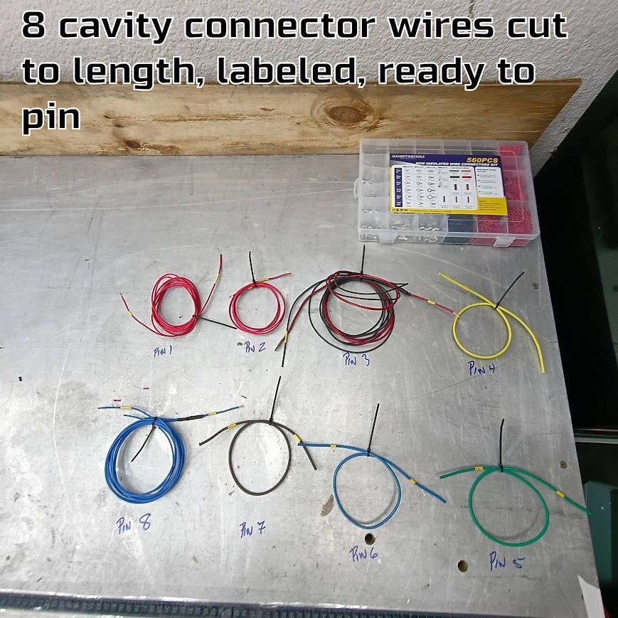 Labeled connector wires cut to length, neatly coiled on a work surface beside a parts box.