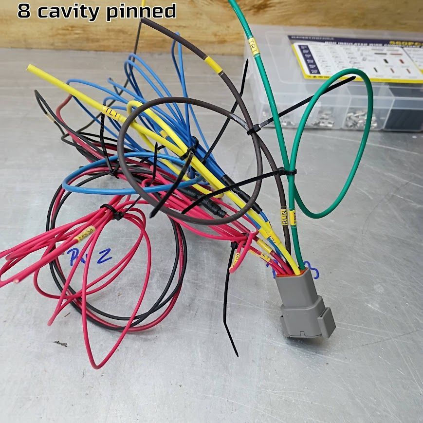 Cluster of multicolored jumper wires with gray connector on a metal table, labeled “8 cavity pinned”