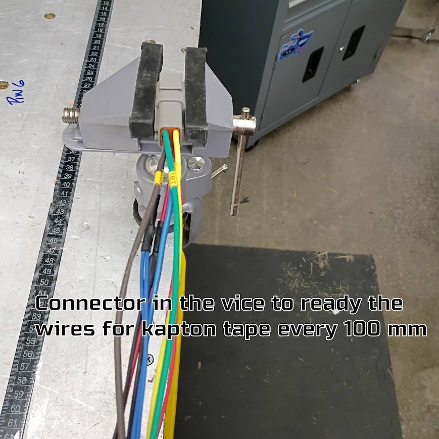 Clamped multicolored wires in a workshop, with text about arranging connectors every 100 mm