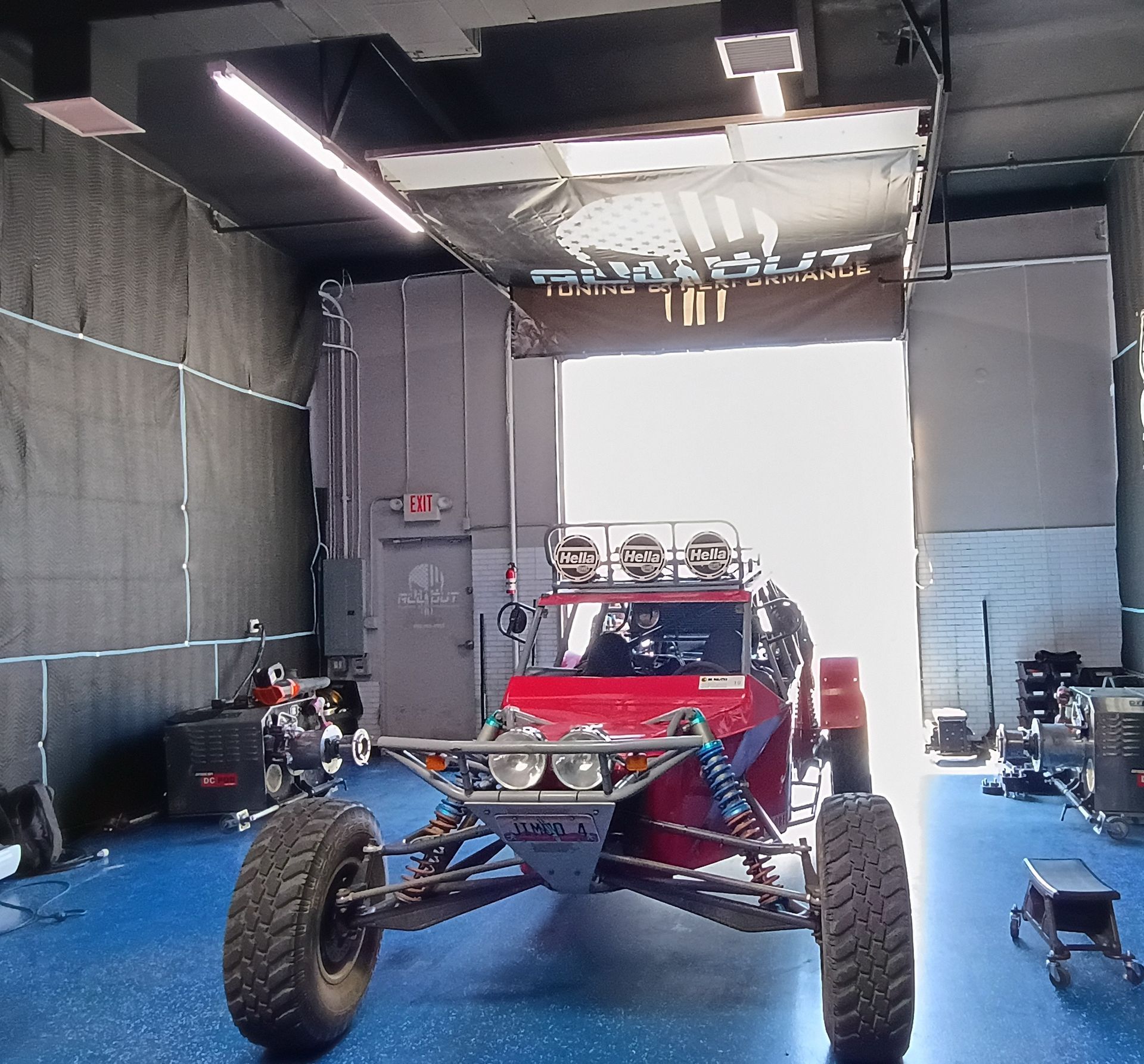 Red off-road buggy in a garage with bright open doorway behind it