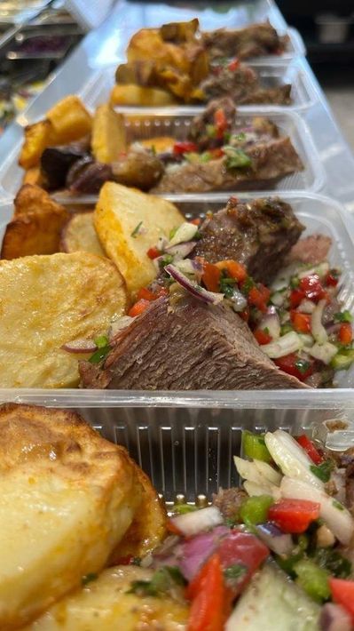 Bandeja para llevar con carne a la parrilla, arroz, plátano frito y salsa fresca en compartimentos.