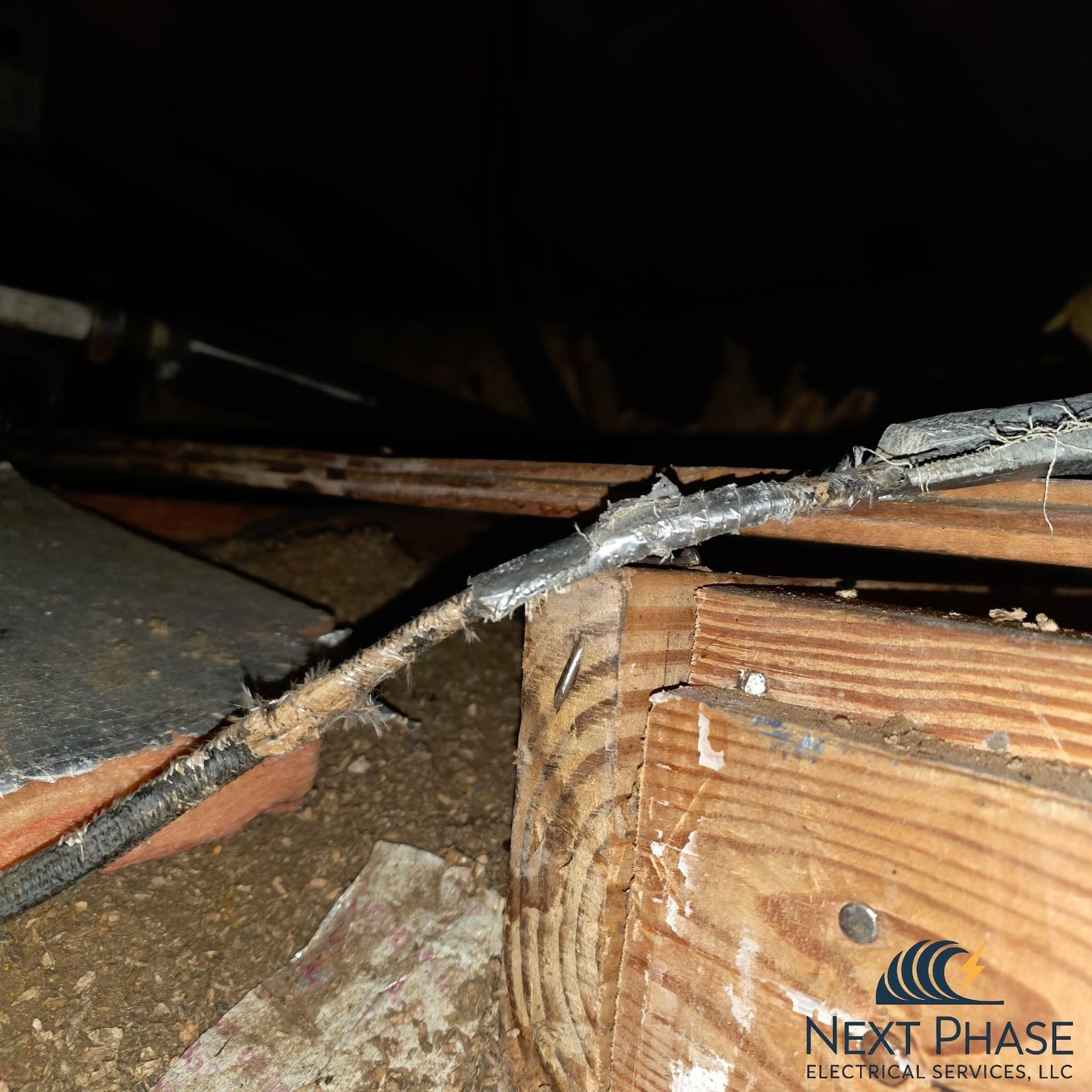 Electrician working with wires inside a ceiling junction box mounted on a metal rail.