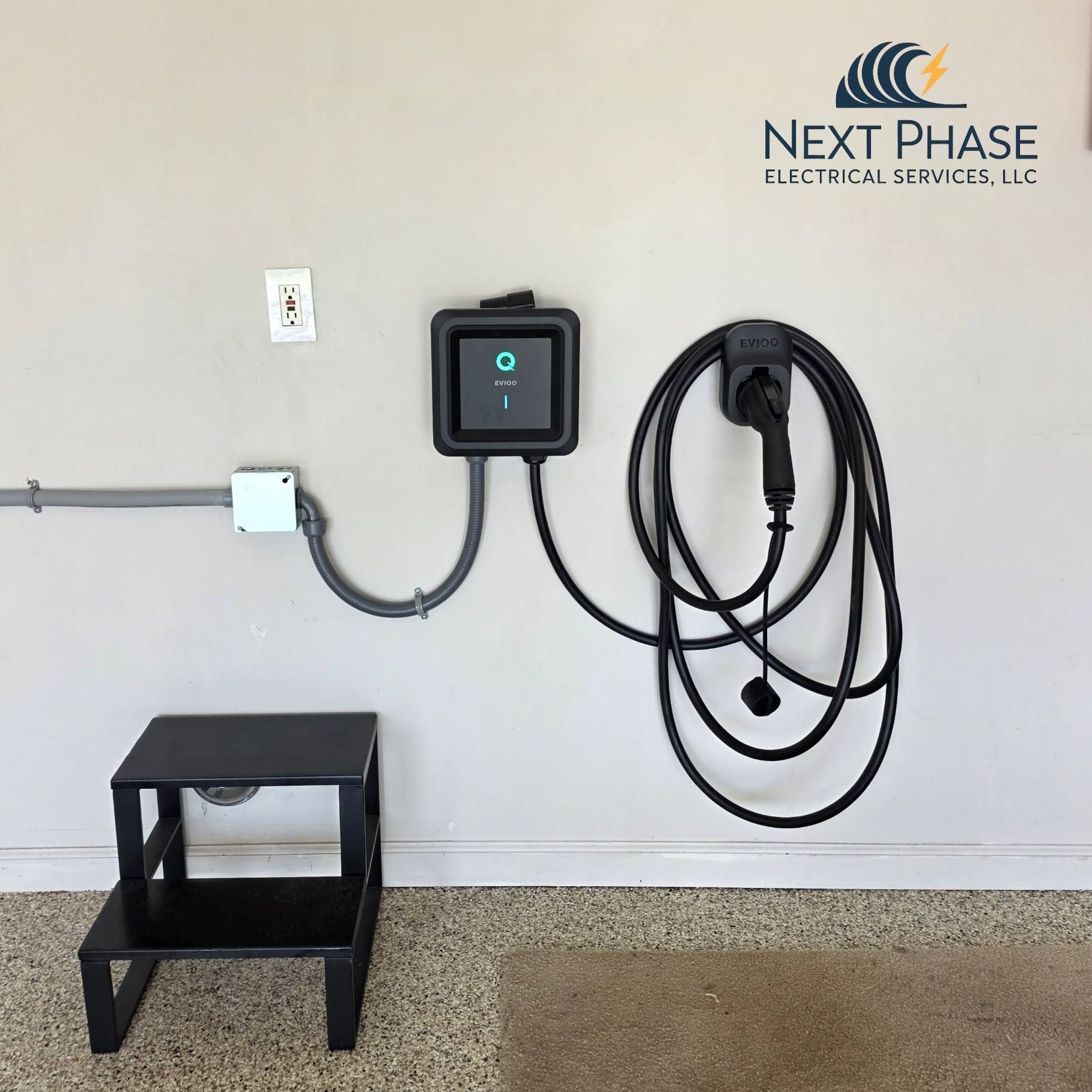 White electric vehicle charging station with two charging cables, outdoors.