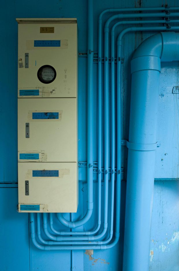 Electrical panel and blue pipes against a blue wall.
