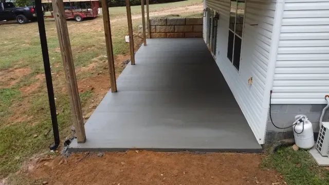 A concrete porch is being built on the side of a house.