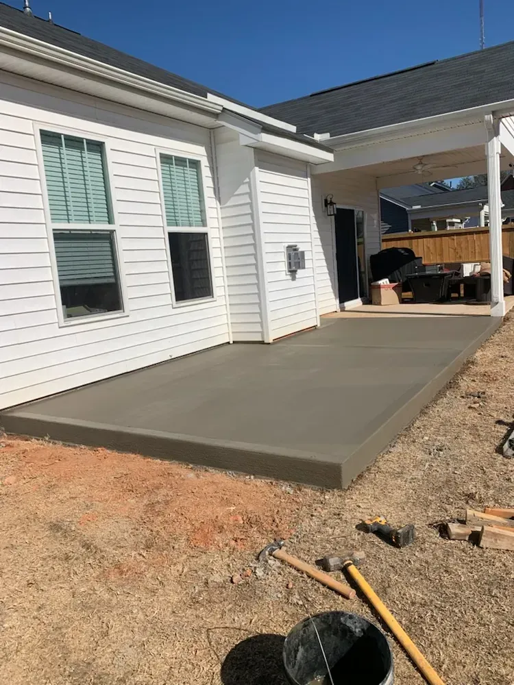 A concrete patio is being built in front of a house.