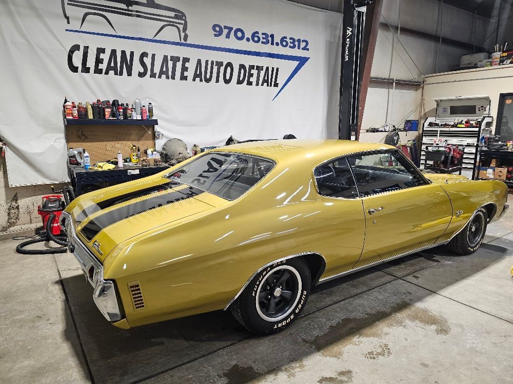 Yellow classic muscle car with black racing stripes in an auto detail shop