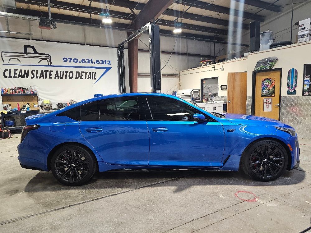 Blue sedan with black rims parked inside an auto detailing shop